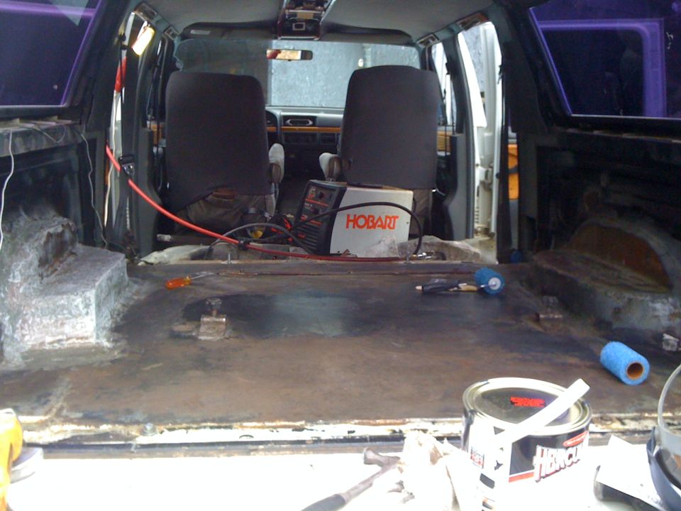 Interior of a van with seats removed, showing a Hobart welder and tools on the floor