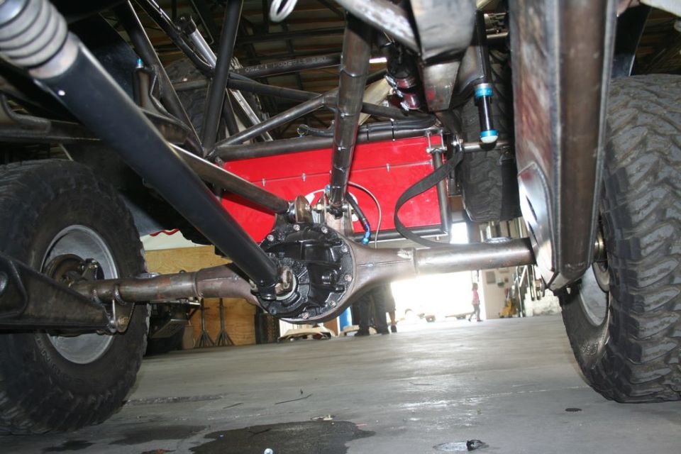 Undercarriage view showing rear axle, differential, 4-link suspension, blue shocks and red tank.