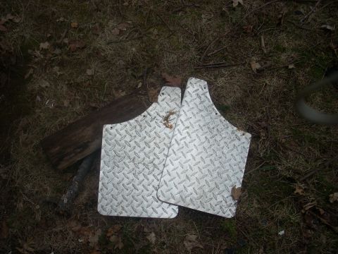 1996 Ford Bronco - Diamond plate mud flaps are shown lying on the ground next to a piece of wood.