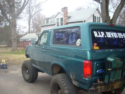 1996 Ford Bronco - This lifted green SUV features off-road tires and a memorial decal on its rear window.
