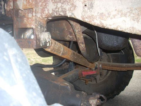 1996 Ford Bronco - Undercarriage view showing worn and rusted suspension parts, including a tie rod and leaf spring.
