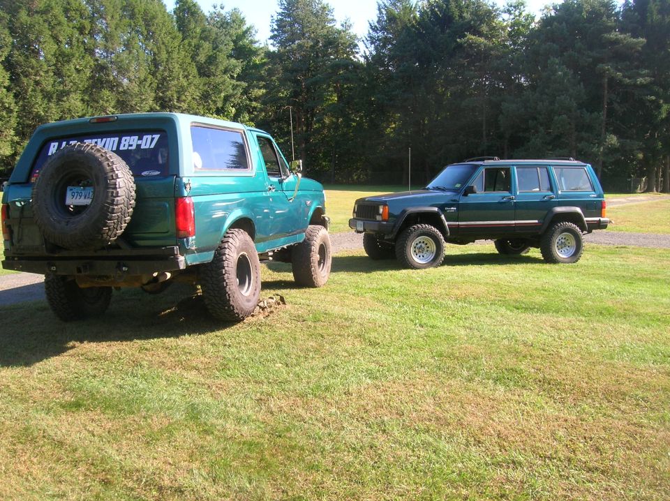 Green 1995 Jeep Cherokee parked next to a green Ford Bronco