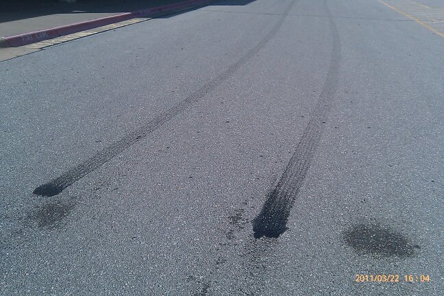 Tire marks and fluid stains on asphalt road surface