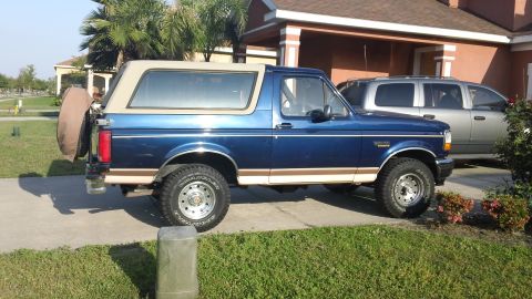 1994 Ford Bronco - Side view of a blue 1994 Ford Bronco parked in a driveway next to a silver SUV.