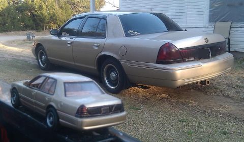 2000 Mercury Grand Marquis - A tan sedan is parked next to a toy model of the same car, showing a rear 3/4 perspective.