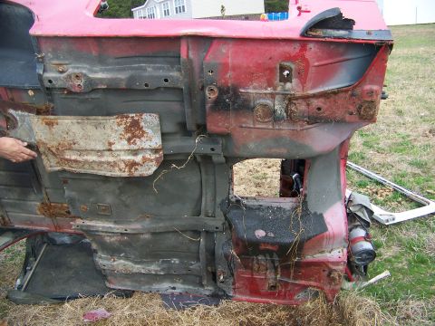1992 Jeep YJ - Underside view of a red 1992 Jeep YJ frame showing significant rust and damage.