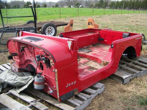 1992 Jeep YJ - This red 1992 Jeep YJ body is displayed on wooden pallets, with the side and front firewall clearly visible.