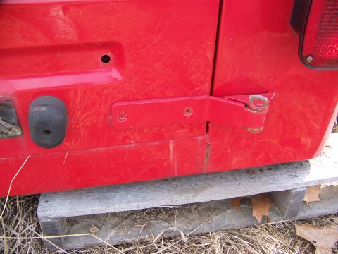 1992 Jeep YJ - Close-up of a red Jeep's rear door hinge and latch, showing some wear.