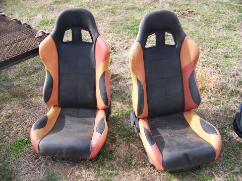 1992 Jeep YJ - Two aftermarket racing seats with black and orange upholstery are displayed outdoors on a grassy area.