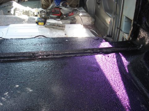 1992 Ford C-350 (Centurion Conversions) - Applying sound deadening material to the interior floor of a vehicle. Tools are present in the background.