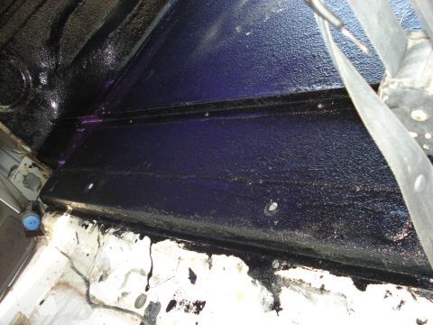1992 Ford C-350 (Centurion Conversions) - Close-up of the interior floor and frame showing undercoating and a seatbelt.