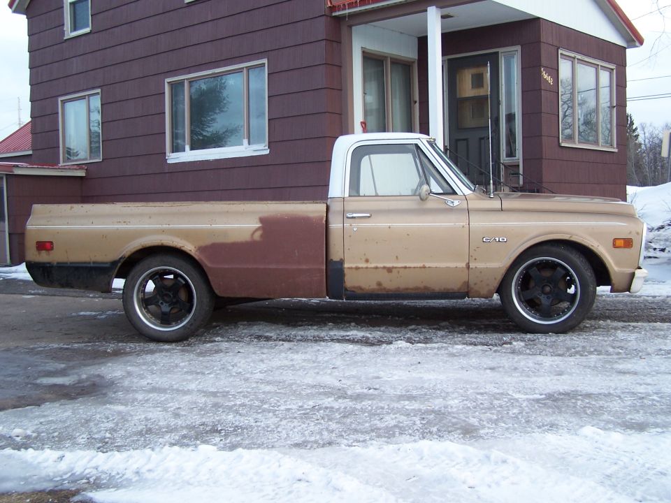 Tan and brown 1969 Chevrolet C/K Pickup with a white roof, seen from the side in front of a house