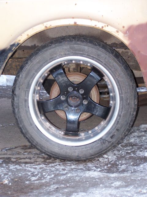 1969 Chevrolet C/K Pickup - A close-up view of a vehicle's wheel and tire, showing aftermarket rims and a rusty fender.