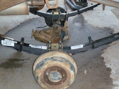 1992 Ford Mustang - Close-up view of a vehicle's rear axle and leaf springs, showing the brake drum and suspension components.