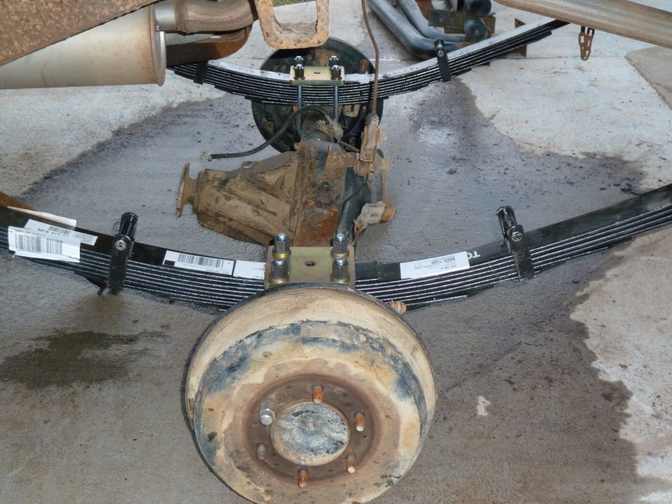 Rear axle on concrete with new leaf springs, U-bolt plates and rusty brake drum