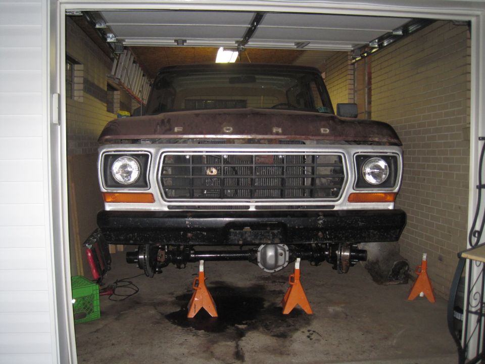 Front view of a 1979 Ford Bronco with its front suspension disassembled and supported by jack stands