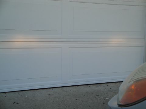 2003 Ford Taurus - A car's headlight is visible in the foreground, with a white garage door behind it.