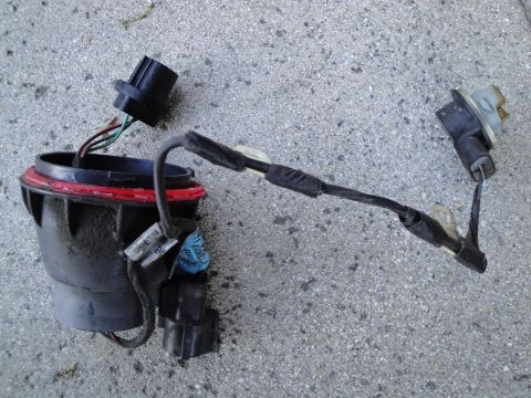 2003 Ford Taurus - A detached headlight wiring harness lies on a concrete surface, showing its connectors and wiring.