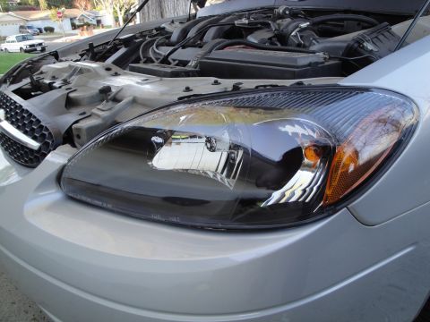 2003 Ford Taurus - Close-up of a 2003 Ford Taurus headlight and engine compartment.