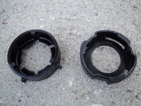 2003 Ford Taurus - Two black plastic headlight retaining rings are shown on a concrete surface.