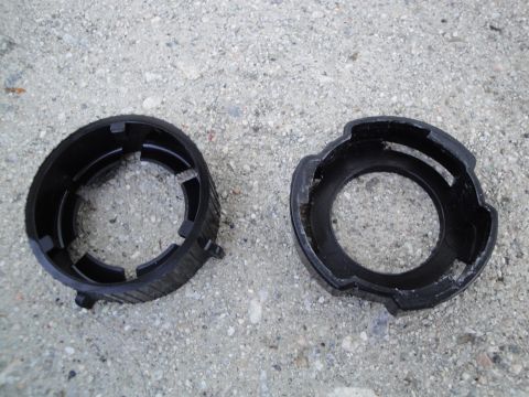 2003 Ford Taurus - Two black plastic headlight retainer rings are shown on a concrete surface.