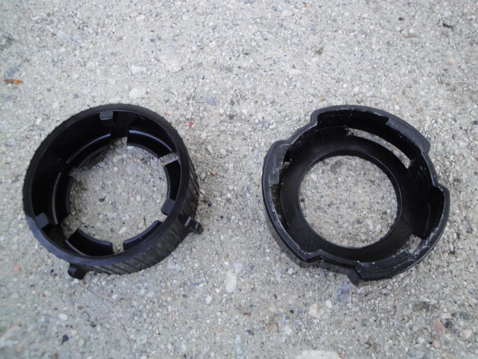 Two black plastic headlight retainer rings on a concrete surface