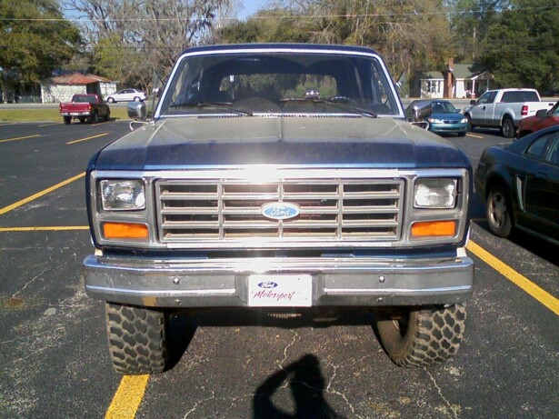 Front view of a blue and gray Ford Bronco with a chrome bumper and off-road tires