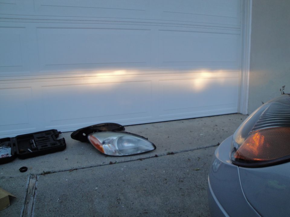 headlights and a tool kit on the ground in front of a garage door