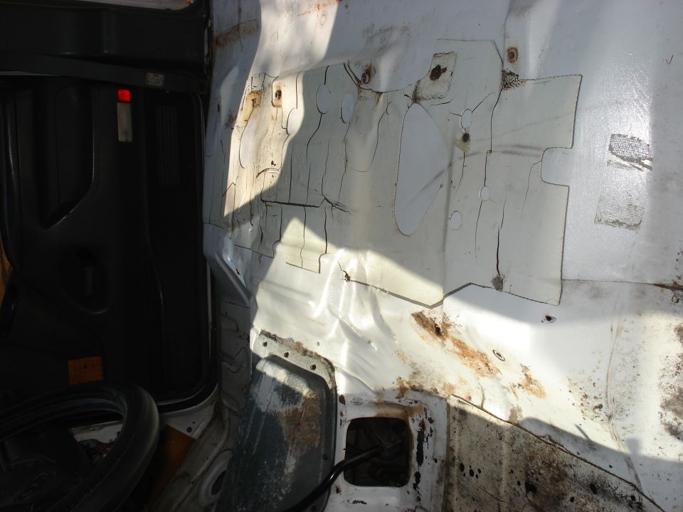 Bare white-painted truck cab floor pan with surface rust, seats and carpet removed