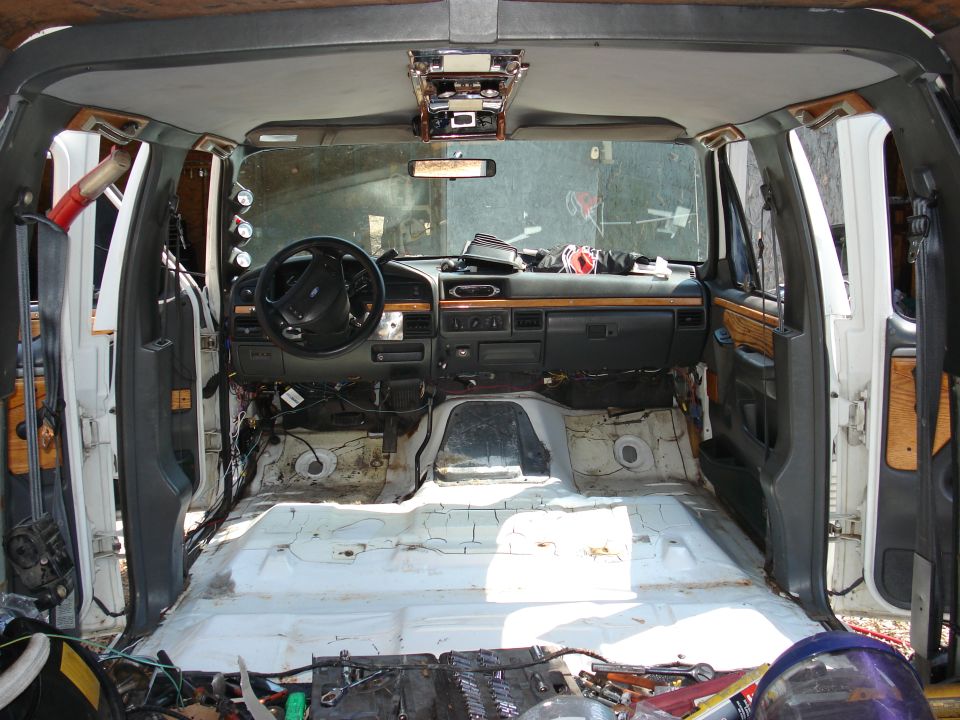 Stripped Ford truck cab interior, bare white floor, woodgrain dash, overhead gauge console