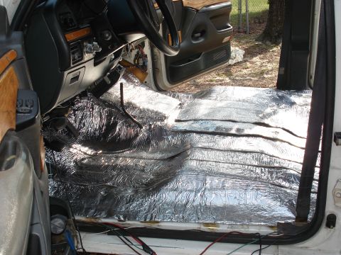 1992 Ford C-350 (Centurion Conversions) - Interior shot through the open driver's door of a gutted truck cab, with the floor pan fully covered in foil-faced sound-deadening mat. Sea…