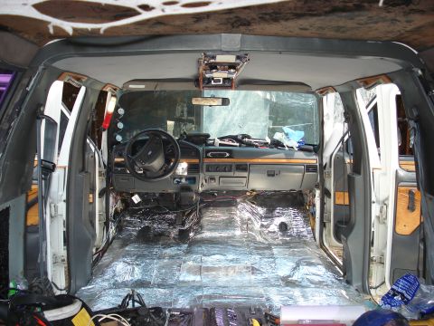 1992 Ford C-350 (Centurion Conversions) - The interior of a van is being worked on, with soundproofing material covering the floor and parts of the doors.