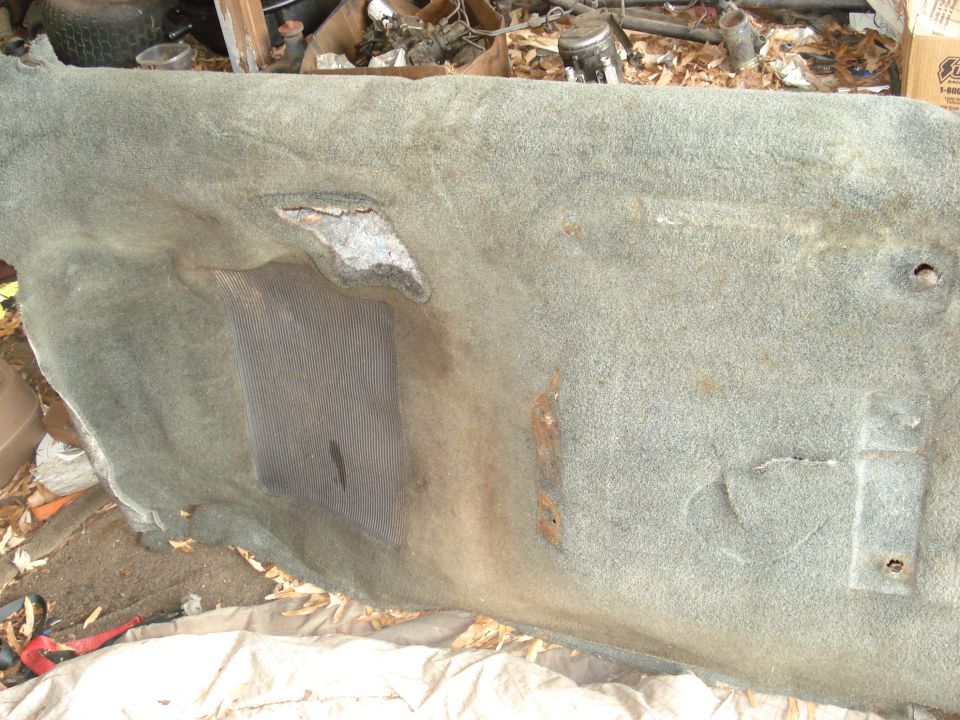 Worn, torn carpet piece with a mesh insert and rust stains