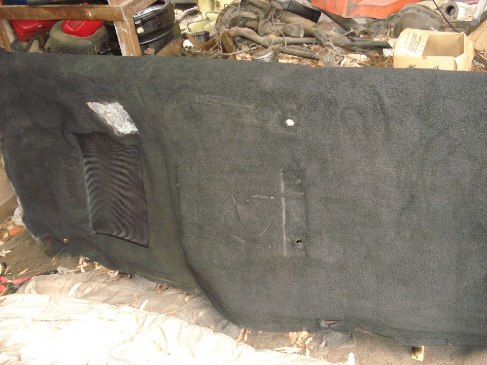 Dark gray carpeted interior panel with two rectangular cutouts, one with a black insert