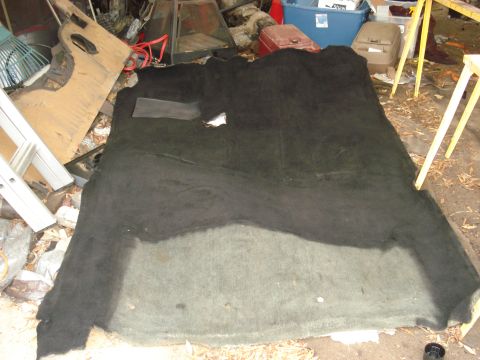 1992 Ford C-350 (Centurion Conversions) - A large piece of dark vehicle carpet is spread out on the ground, with various items in the background.