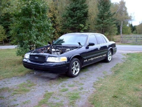 2000 Ford Crown Victoria - Three-quarter front driver-side view of a black Ford Crown Victoria parked on a grass and gravel driveway with the hood removed, exposing t…