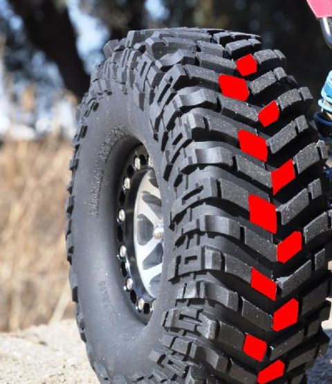 1996 Ford Bronco - A close-up view of an off-road tire, highlighting its aggressive tread pattern with red markings.