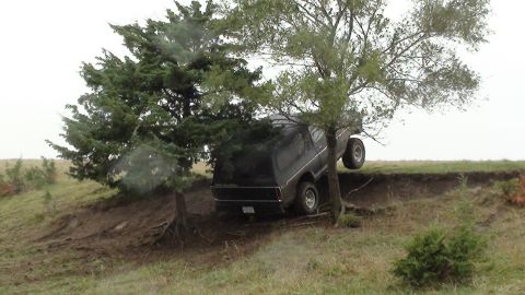 1978 Ford Bronco - This 1978 Ford Bronco is precariously positioned on a steep, muddy incline, caught between two trees.