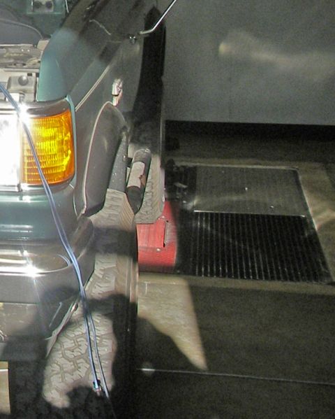 1990 Ford Bronco - The front wheel and fender of an SUV are shown, with a red chock positioned under the tire.