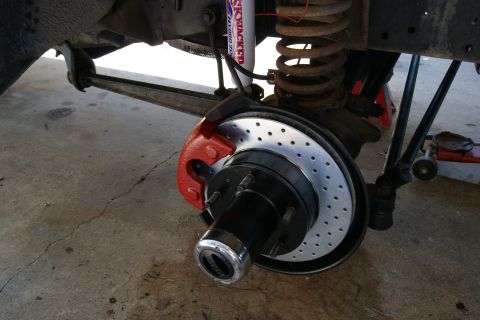 1978 Ford Bronco - Close-up of a vehicle's brake system, showing a red caliper and a drilled rotor.
