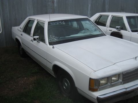 1991 Ford Crown Victoria LTD - A white 1991 Ford Crown Victoria LTD is parked outside next to another vehicle. Text is visible on the windshield.
