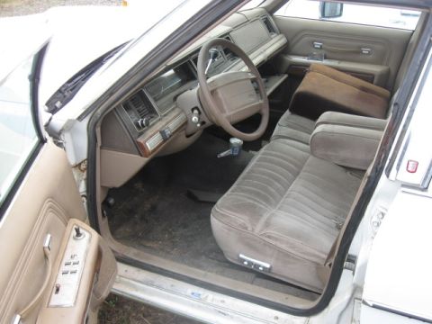 1991 Ford Crown Victoria LTD - The interior of a sedan shows a tan dashboard, steering wheel, and velour seats.