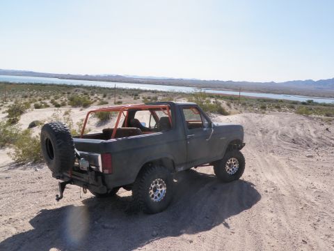1982 Ford Bronco - This 1982 Ford Bronco is shown off-roading in a desert landscape with a lake in the background.