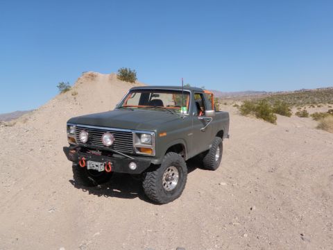 1982 Ford Bronco - This modified Ford Bronco is parked in a desert landscape under a clear blue sky.