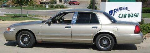 2000 Mercury Grand Marquis - Side view of a gold 2000 Mercury Grand Marquis parked near a car wash.