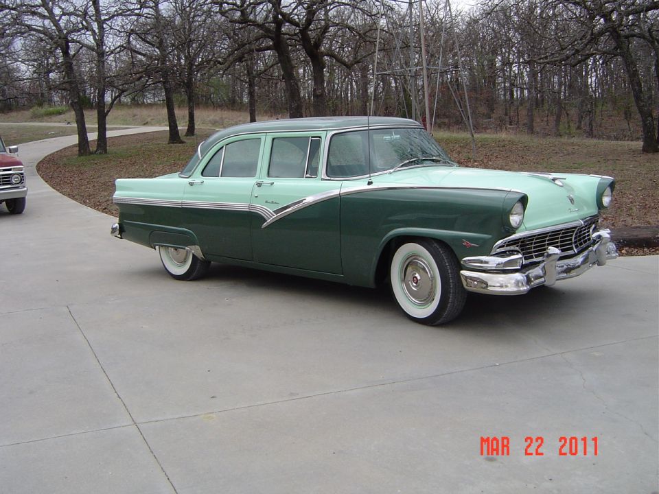 1956 Ford Fairlane sedan, two-tone green and light green, parked on concrete driveway. Another vehicle is partially visible to the left