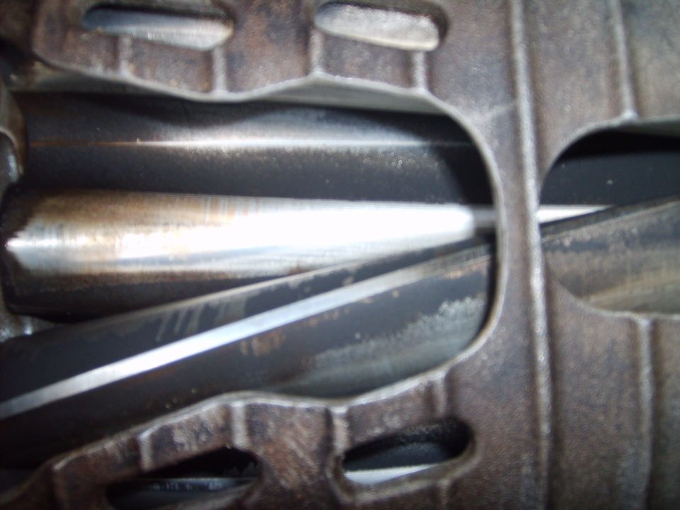 Close-up inside a Roots supercharger case showing polished twisted rotor lobes in the housing bore