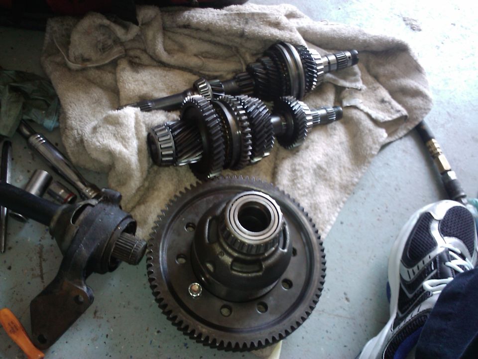 Car transmission gears and differential assembly on a towel with tools and a shoe