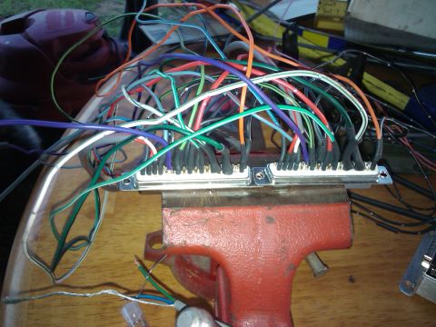 1995 Ford Probe - A complex wiring harness, secured in a vise, displays a multitude of colorful wires connected to two silver terminal blocks.
