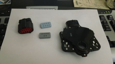 1994 Ford Bronco - Transmission range sensor and electrical connector with two gray plugs are laid out on a paper.